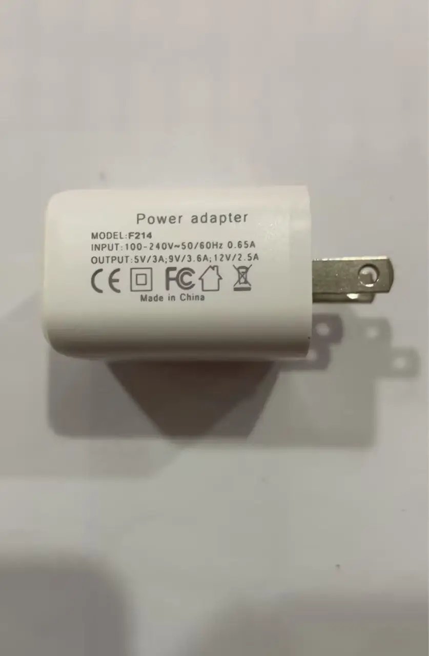 White power adapter brick with plug, labeled model F214 and input/output specs