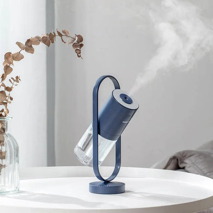 Blue USB ultrasonic mini humidifier with projection night light on a curved stand.